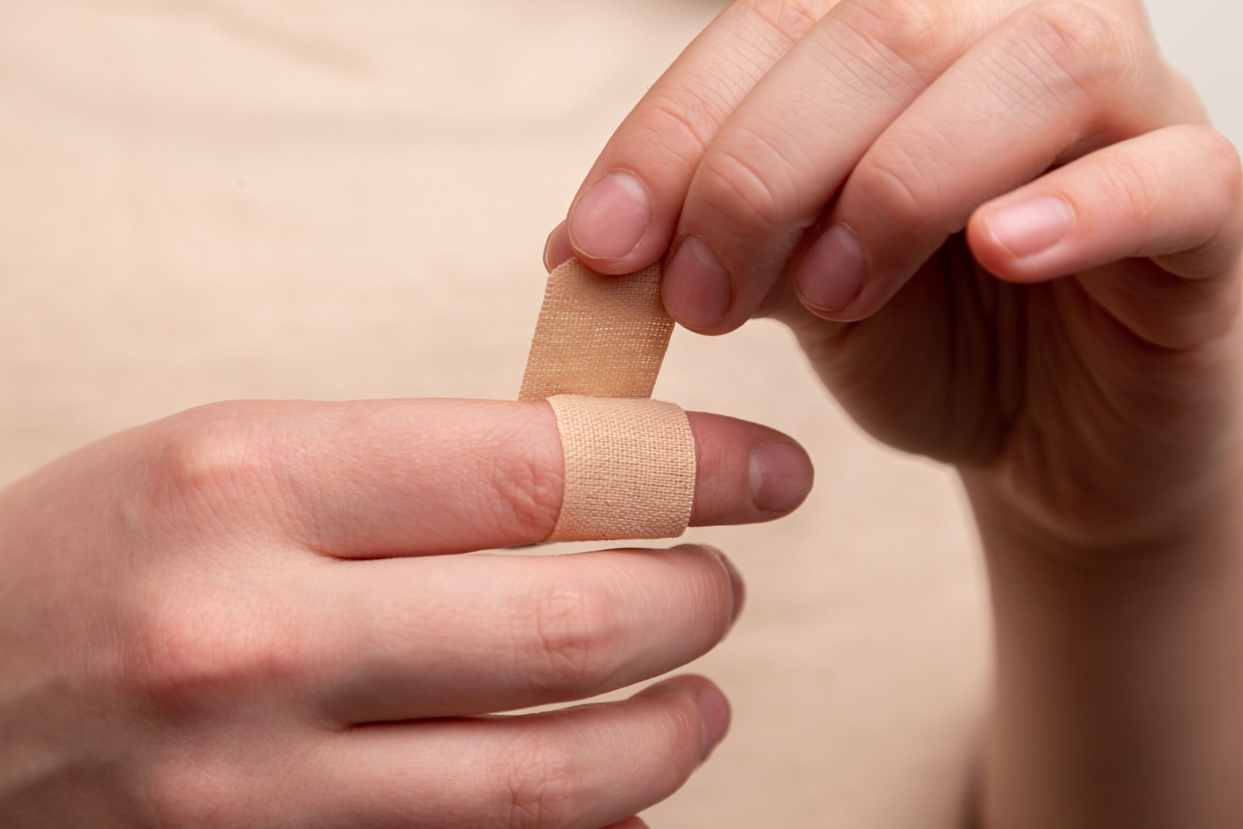 Stock photo of a person applying a Band-Aid to their index finger.